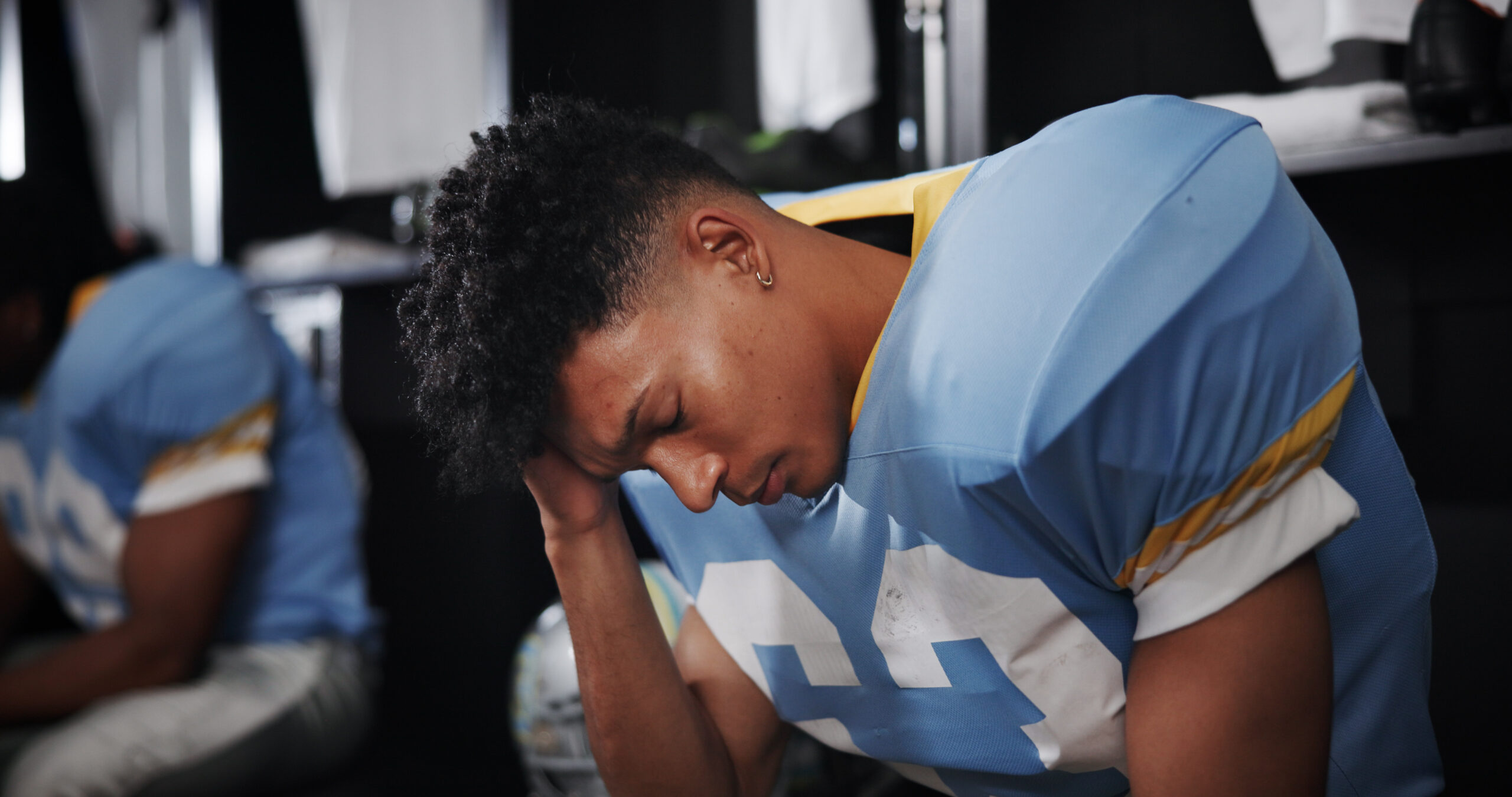 Man, American football player and headache with stress in locker room, frustrated or concussion with sport injury. Person, migraine and professional athlete with cte, tired and burnout at franchise.
